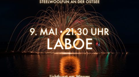 Maifeuer am Ostseestrand mit Stahlwoll-Fontäne vor glühendem Himmel