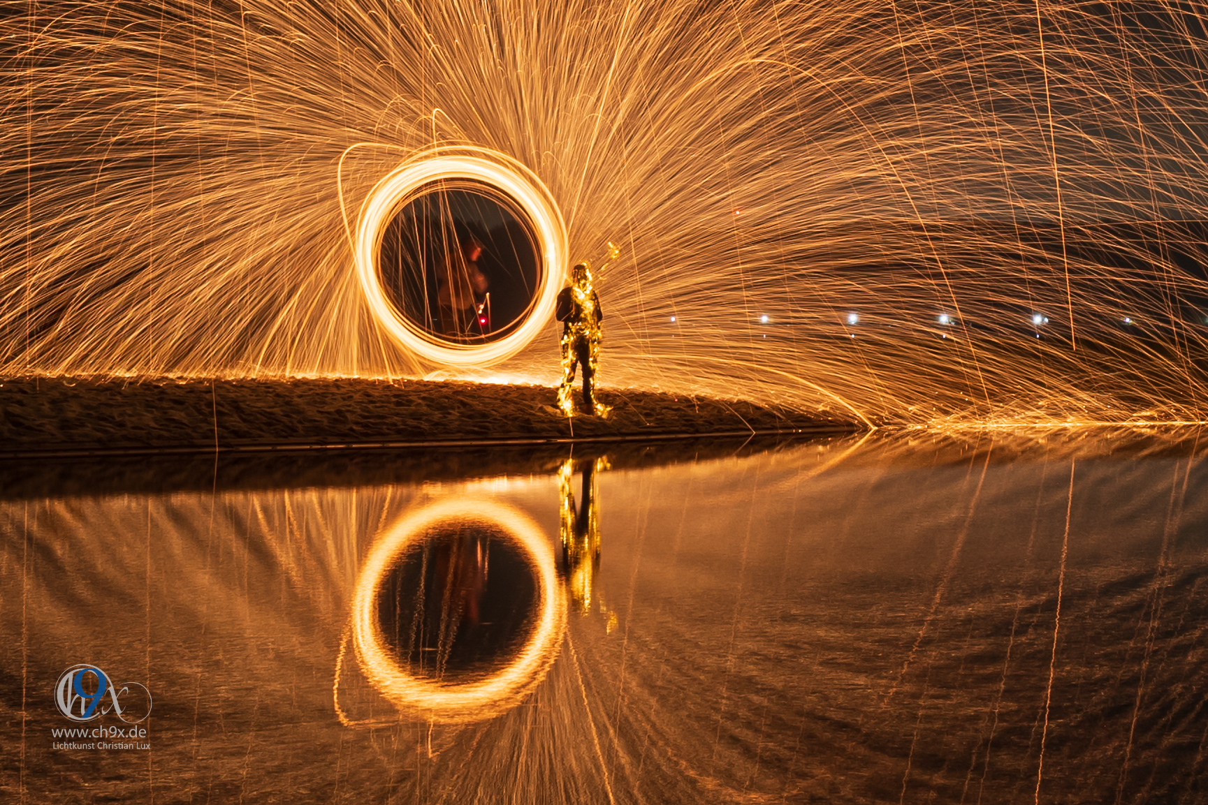 Feuer-Spirale aus brennender Stahlwolle am Strand bei Nacht